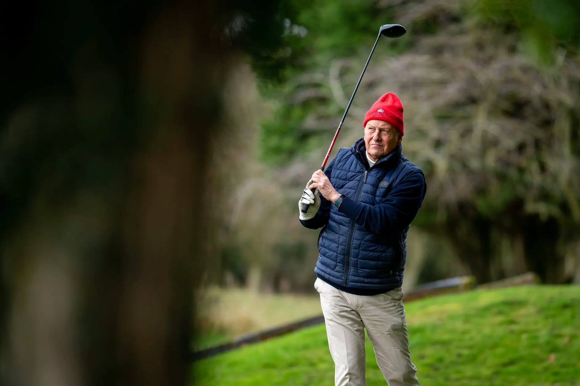 elderly man in red winter hat holding golf stick