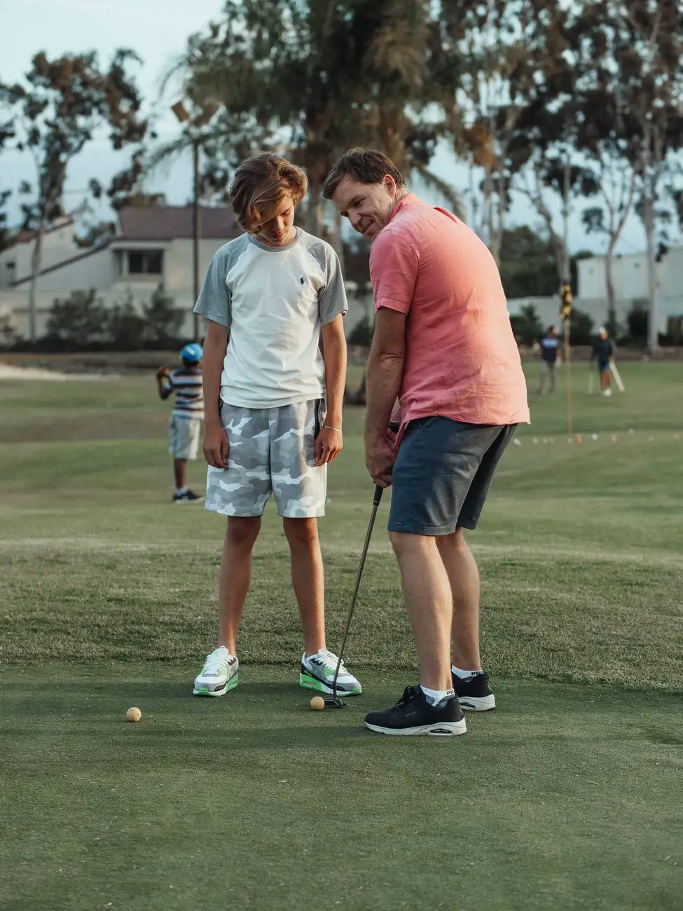a son standing beside his father playing golf